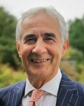 Portrait of Gianni Angelini in a dark pinstripe suit and pink tie